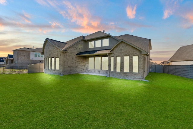 back house at dusk with a lawn