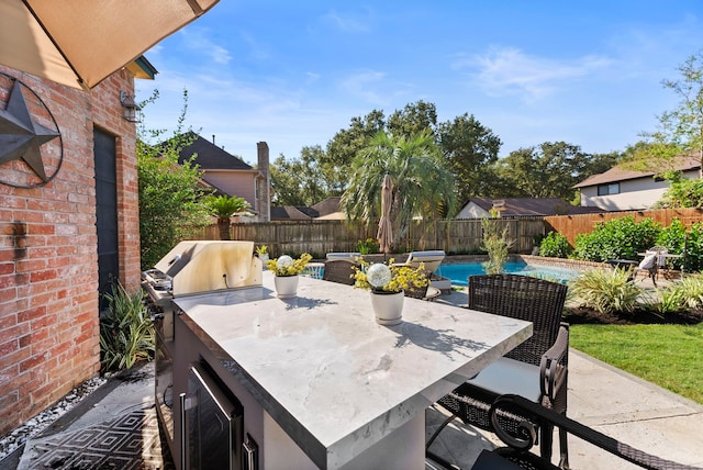 view of patio / terrace featuring a fenced in pool, an outdoor bar, an outdoor kitchen, area for grilling, and a fenced backyard