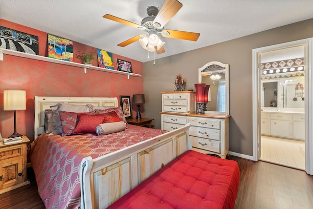 bedroom featuring a ceiling fan, baseboards, dark wood finished floors, and ensuite bath