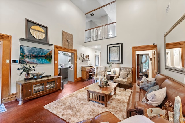 living room with visible vents, dark wood-type flooring, a high ceiling, and baseboards