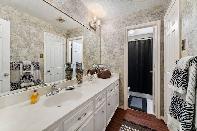 full bath with visible vents, a sink, a textured ceiling, and double vanity