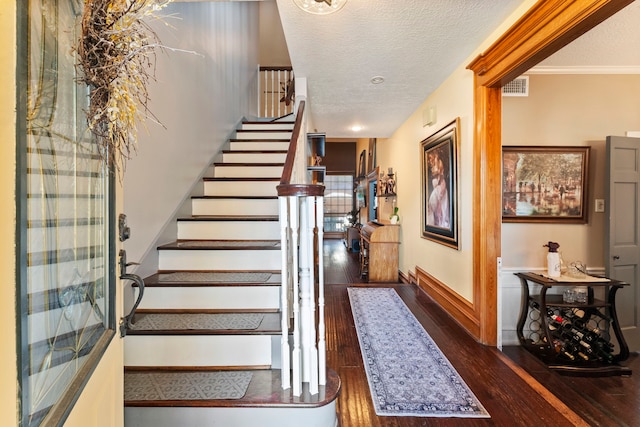 foyer entrance featuring dark wood-style flooring, visible vents, a textured ceiling, and baseboards