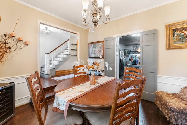 dining area with an inviting chandelier, dark wood-style floors, crown molding, and wainscoting