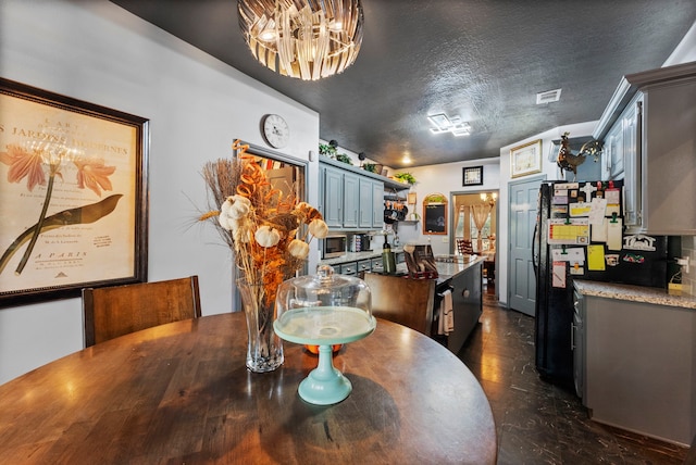 dining space featuring a textured ceiling, a chandelier, and visible vents