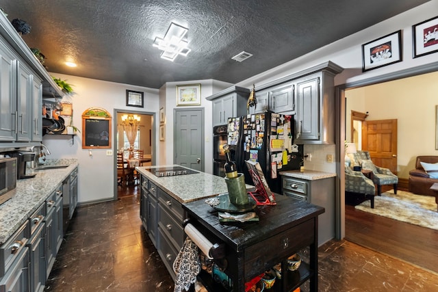 kitchen featuring a sink, light stone countertops, a textured ceiling, black appliances, and backsplash