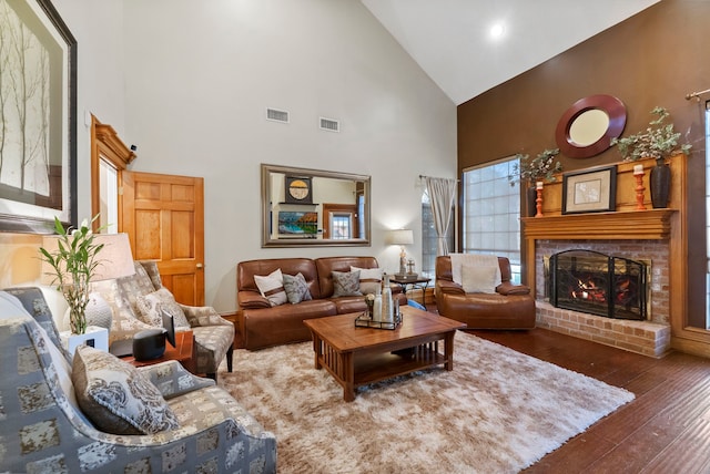 living room with dark wood-style floors, visible vents, a fireplace, and high vaulted ceiling