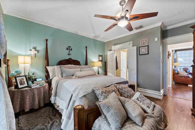 bedroom with baseboards, visible vents, ceiling fan, ornamental molding, and wood finished floors