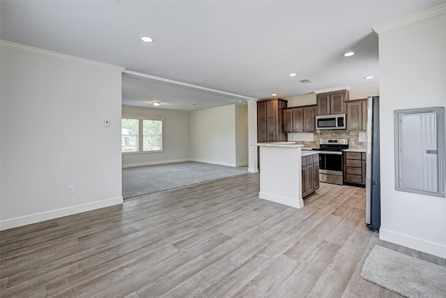 kitchen featuring ornamental molding, stainless steel appliances, light hardwood / wood-style floors, and a center island