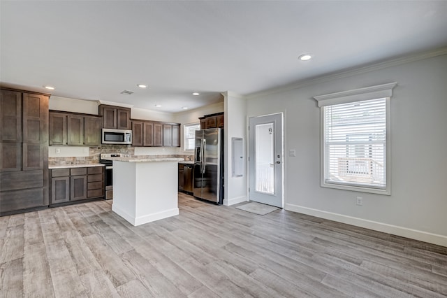 kitchen with appliances with stainless steel finishes, a center island, light wood-type flooring, and dark brown cabinets