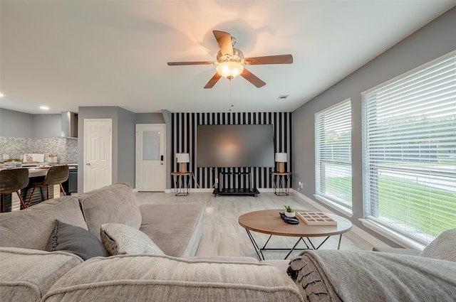 living room featuring light hardwood / wood-style flooring, ceiling fan, and a healthy amount of sunlight