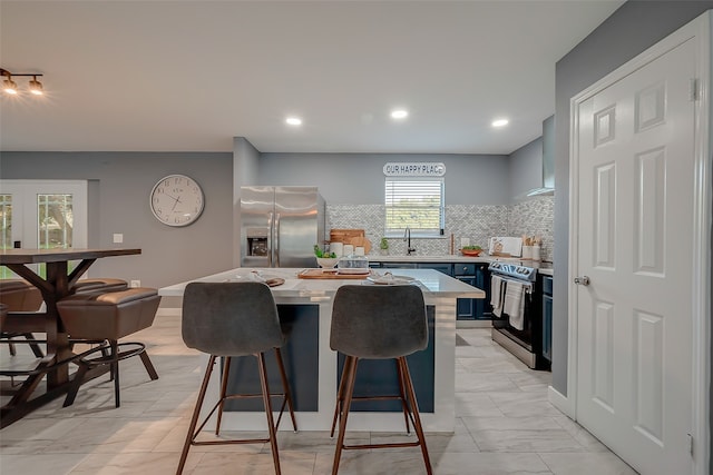 kitchen featuring a breakfast bar, backsplash, blue cabinetry, stainless steel appliances, and a center island