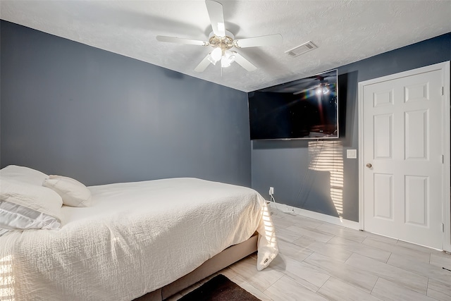 bedroom with ceiling fan and a textured ceiling