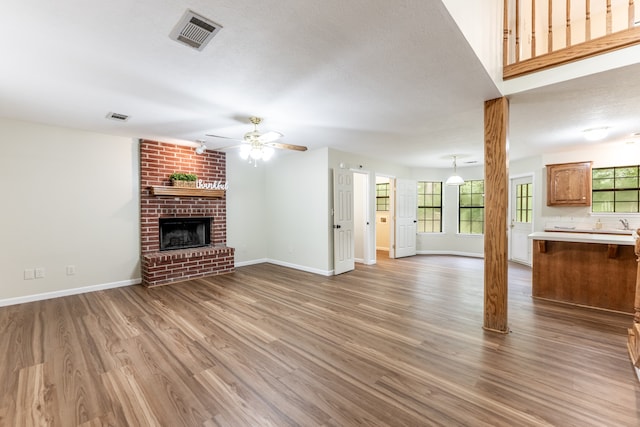 unfurnished living room with light hardwood / wood-style floors, a fireplace, ceiling fan, and plenty of natural light