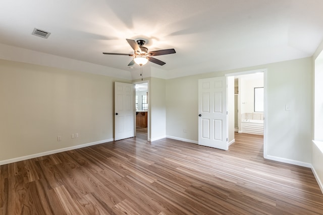 unfurnished bedroom with light wood-type flooring, ceiling fan, and connected bathroom