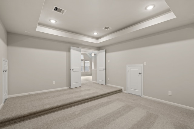 unfurnished bedroom featuring light carpet and a tray ceiling