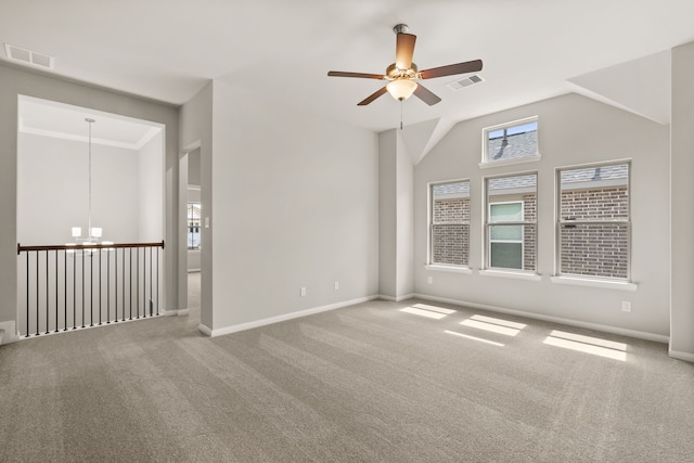 carpeted spare room featuring vaulted ceiling and ceiling fan with notable chandelier