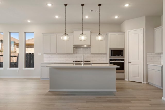 kitchen featuring wall oven, visible vents, white cabinets, light countertops, and pendant lighting