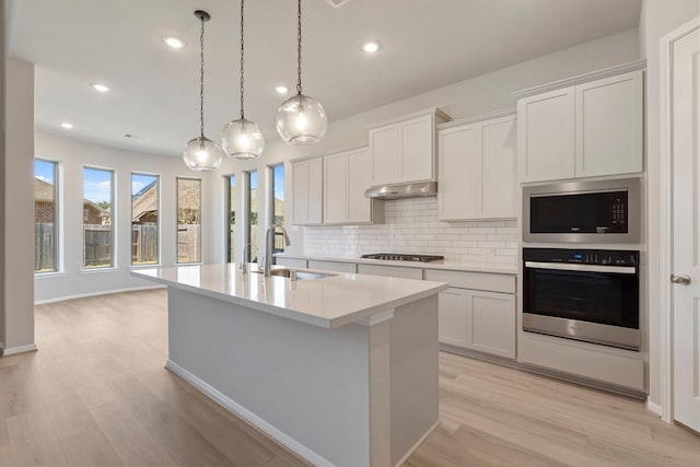 kitchen with light countertops, white cabinetry, stainless steel oven, a sink, and under cabinet range hood