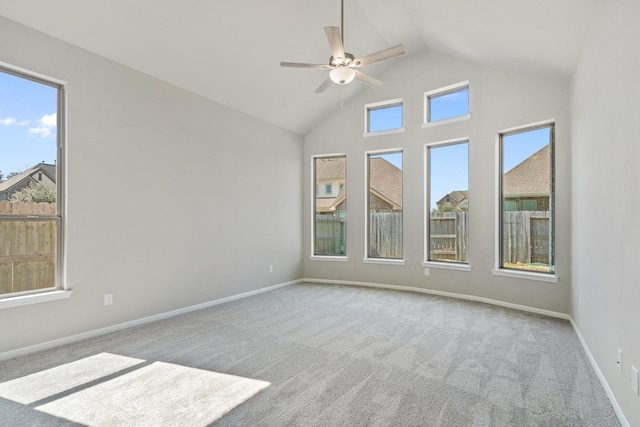 spare room with high vaulted ceiling, a wealth of natural light, light carpet, and baseboards