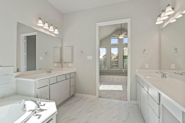 bathroom featuring marble finish floor, two vanities, vaulted ceiling, a sink, and baseboards