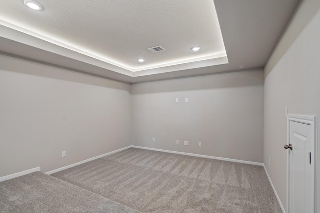 carpeted empty room with recessed lighting, a tray ceiling, visible vents, and baseboards