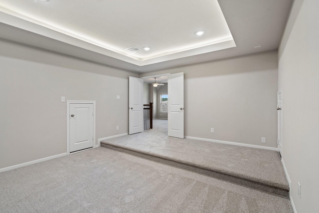 unfurnished room featuring recessed lighting, a raised ceiling, light colored carpet, visible vents, and baseboards