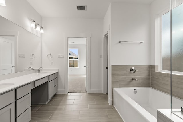 bathroom featuring a bathtub, vanity, and a healthy amount of sunlight