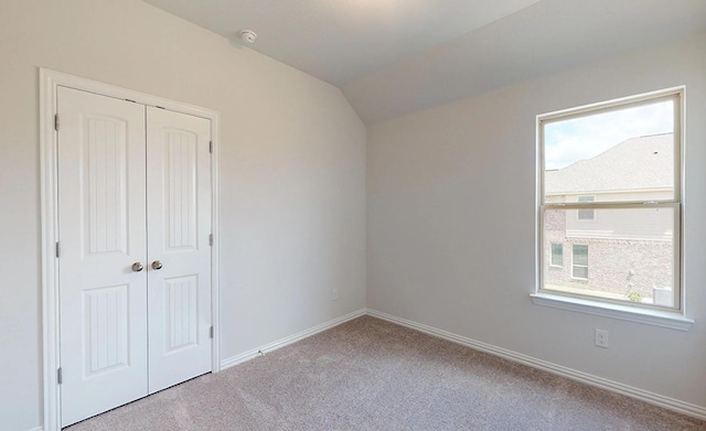 interior space featuring a closet, light carpet, and vaulted ceiling