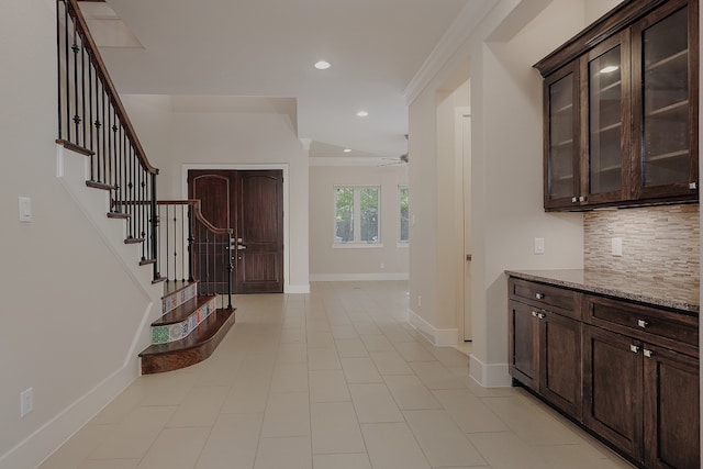 foyer with ceiling fan, light tile patterned flooring, and crown molding