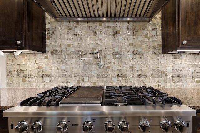 kitchen featuring dark brown cabinetry, stainless steel range, backsplash, and wall chimney range hood