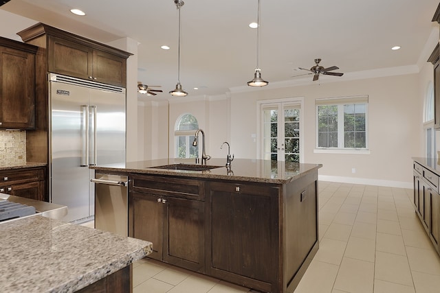 kitchen with tasteful backsplash, pendant lighting, stainless steel appliances, dark brown cabinetry, and sink