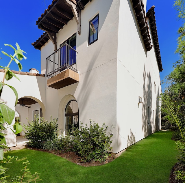 back of property with a balcony and a lawn