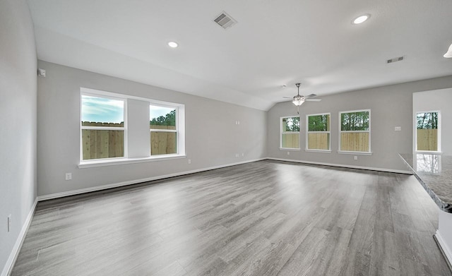 unfurnished room featuring ceiling fan, a healthy amount of sunlight, vaulted ceiling, and hardwood / wood-style flooring