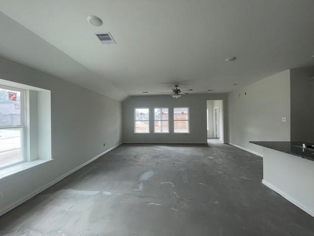 unfurnished living room with ceiling fan, lofted ceiling, and a wealth of natural light