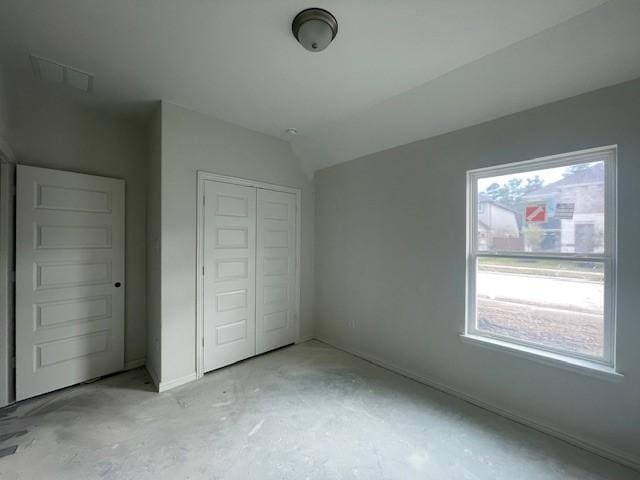 unfurnished bedroom featuring a closet and lofted ceiling