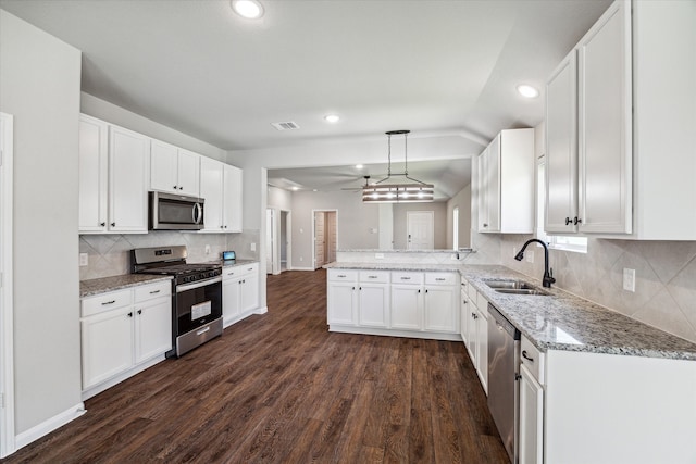 kitchen featuring stainless steel appliances, sink, white cabinets, dark hardwood / wood-style floors, and hanging light fixtures