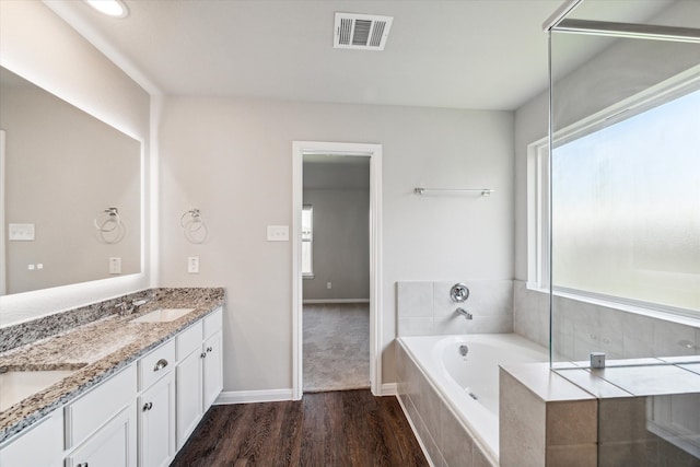 bathroom with hardwood / wood-style flooring, a healthy amount of sunlight, and tiled bath