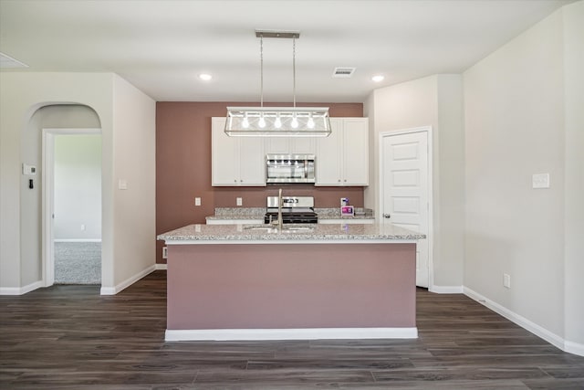 kitchen with white cabinets, light stone countertops, stainless steel appliances, and a kitchen island with sink