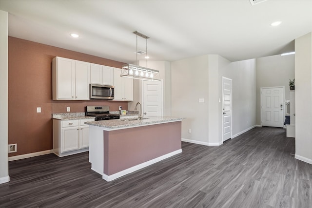 kitchen featuring dark hardwood / wood-style floors, an island with sink, decorative light fixtures, white cabinets, and appliances with stainless steel finishes