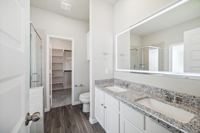 bathroom with toilet, vanity, an enclosed shower, and hardwood / wood-style flooring