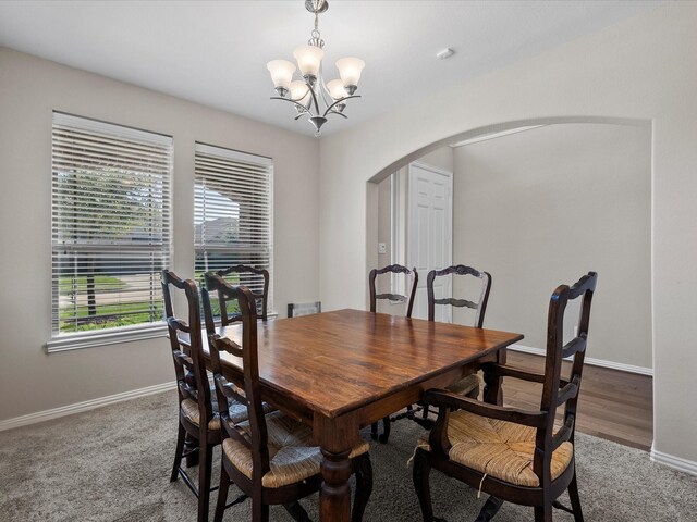 carpeted dining area with an inviting chandelier