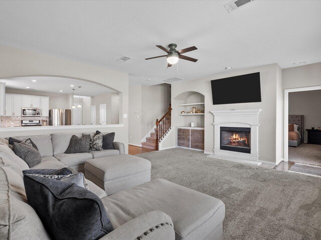 carpeted living room featuring ceiling fan and built in shelves