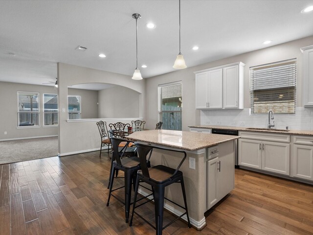 kitchen featuring sink, a center island, white cabinetry, a kitchen breakfast bar, and pendant lighting