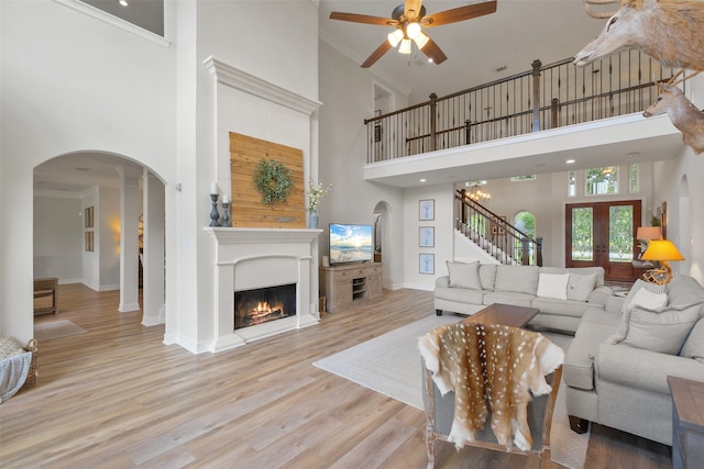 living room featuring light hardwood / wood-style flooring, a towering ceiling, and ornamental molding