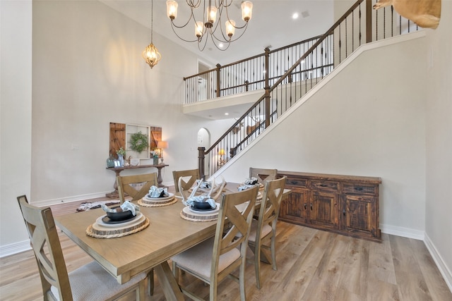 dining space featuring a notable chandelier, a high ceiling, and light wood-type flooring