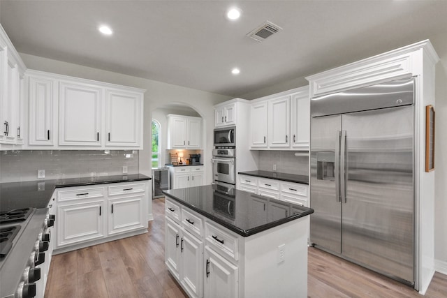 kitchen with white cabinetry, built in appliances, and light hardwood / wood-style flooring