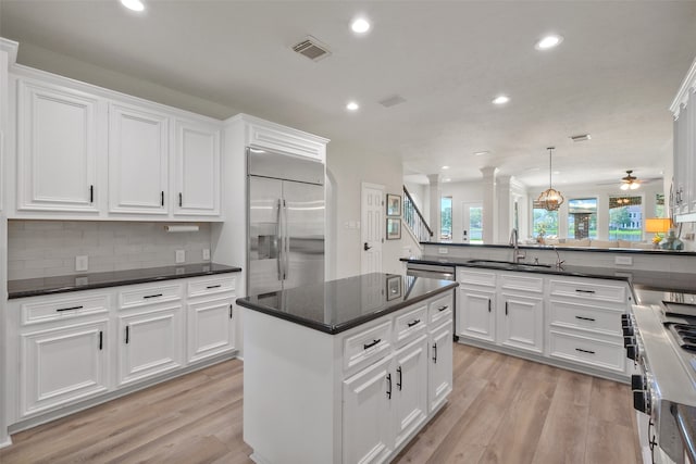 kitchen with hanging light fixtures, kitchen peninsula, light wood-type flooring, built in fridge, and ceiling fan