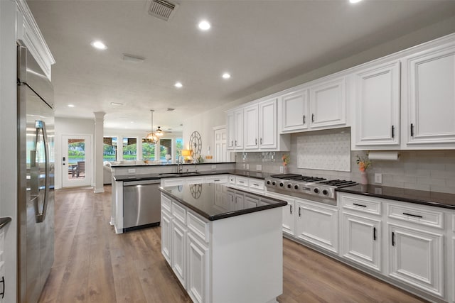 kitchen featuring stainless steel appliances, hanging light fixtures, kitchen peninsula, and a center island