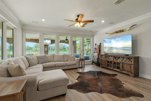 living room featuring a wealth of natural light, light hardwood / wood-style floors, ceiling fan, and crown molding