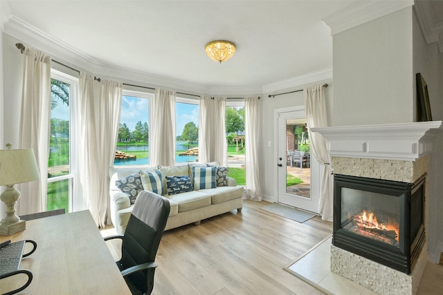 living room featuring a tile fireplace, crown molding, and light hardwood / wood-style flooring